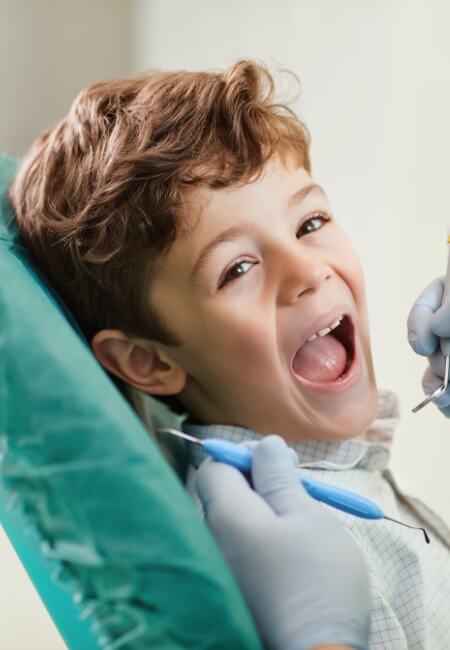 A young boy, seated in a dentist chair