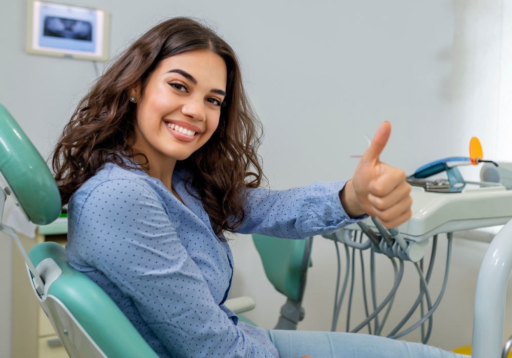 A woman in a dental chair smiles and gives a thumbs up -1