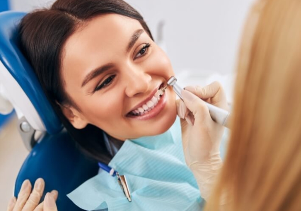 A woman smiles while seated in a dental chair