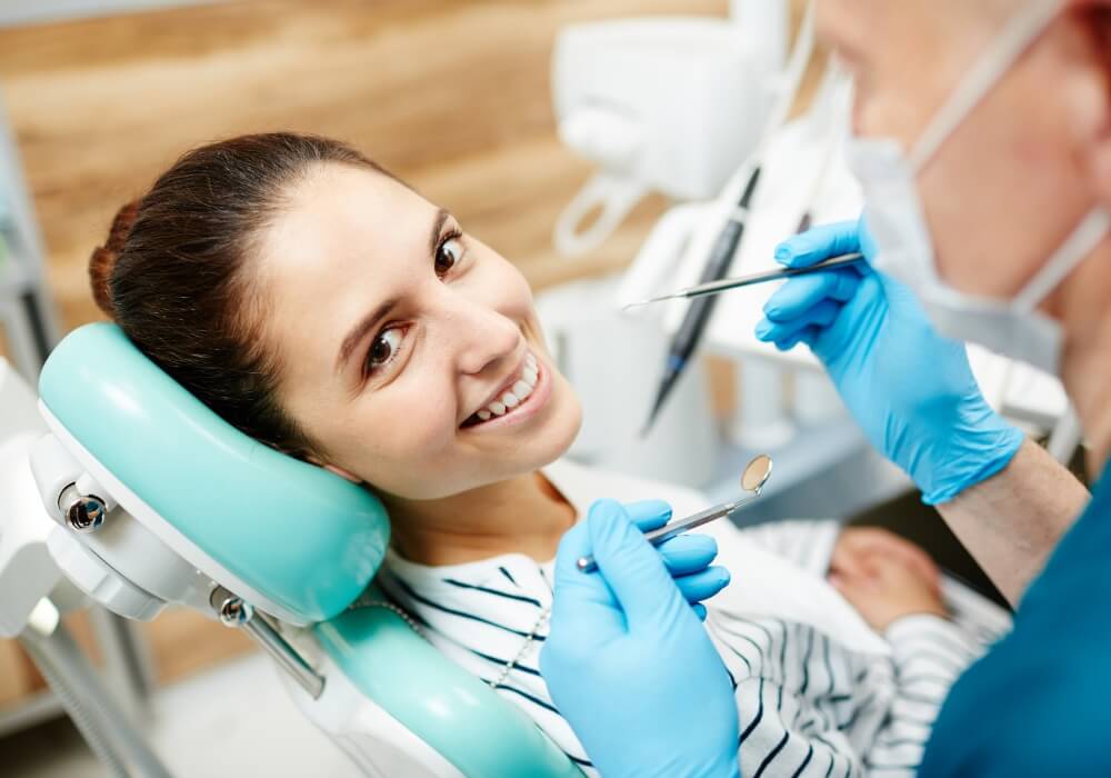 Dentist with tools examining a happy patient