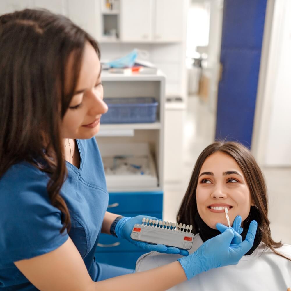 young female dentist trying on dental veneers with patient